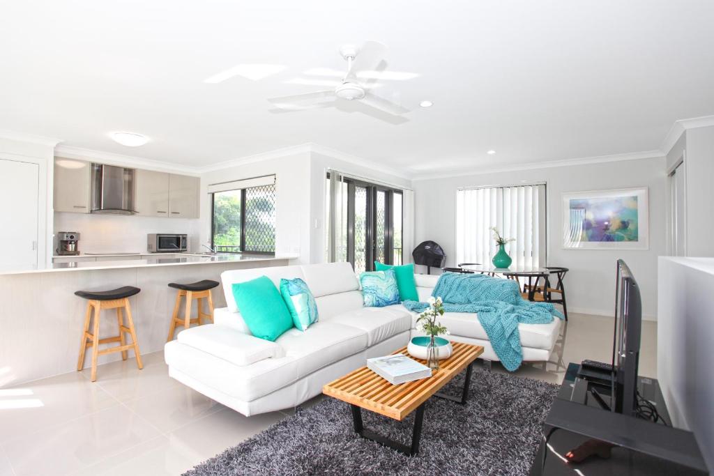 a living room with a white couch and blue pillows at Beach Breeze Holiday House in Mackay