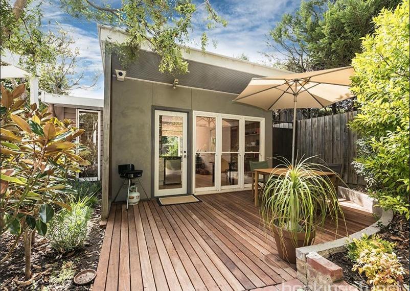 a house with a wooden deck with an umbrella at Garden Cottage St Kilda in Melbourne