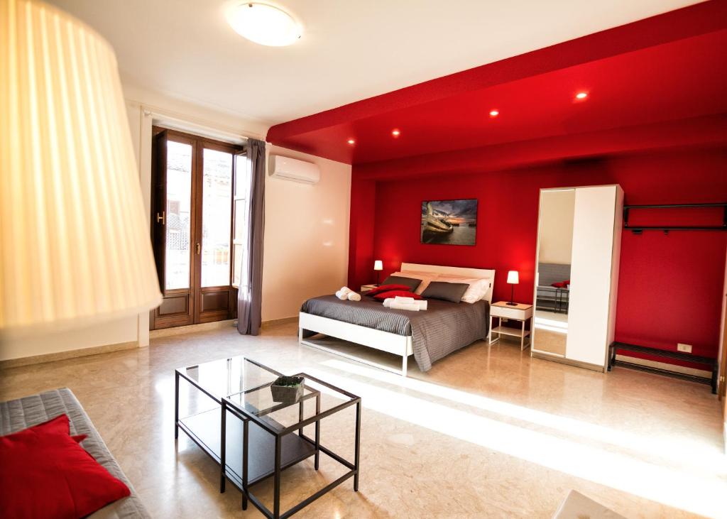 a bedroom with red walls and a bed and a table at Niria in Ragusa
