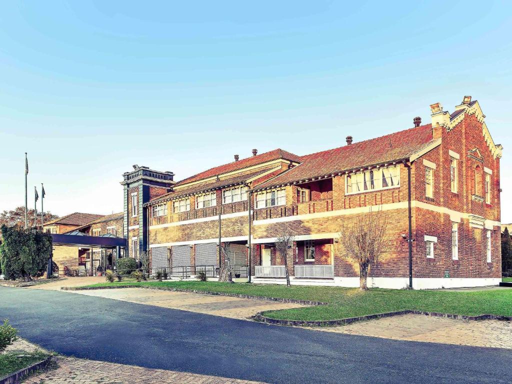 a large brick building with a clock on the front of it at Mercure Maitland Monte Pio in Maitland