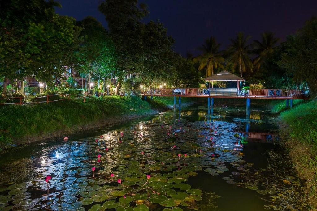 a bridge over a pond with lilies at night at Panpim Resort in Ban Noen Hom