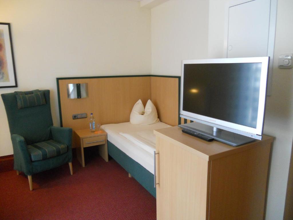 a hotel room with a bed and a tv and a chair at Apartments Aschheim in Aschheim