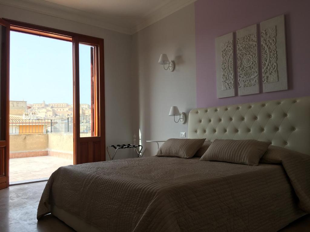 a bedroom with a large bed and a large window at Simonetta's Rooms in Noto