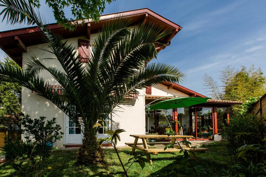 una casa con una mesa y una sombrilla verde en Nami House, en Anglet