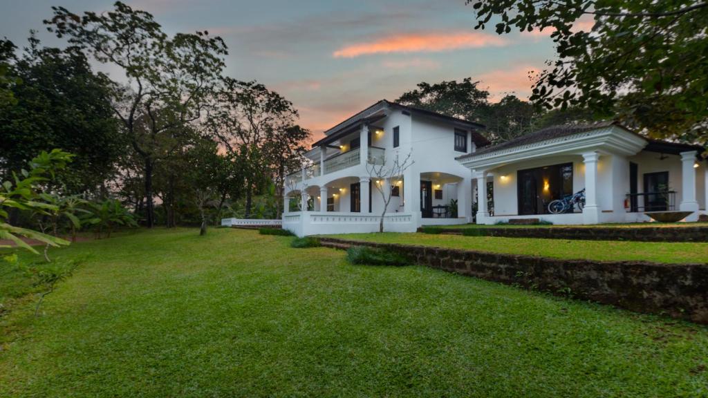 a large white house with a grass yard at The Postcard Velha, Goa in Old Goa