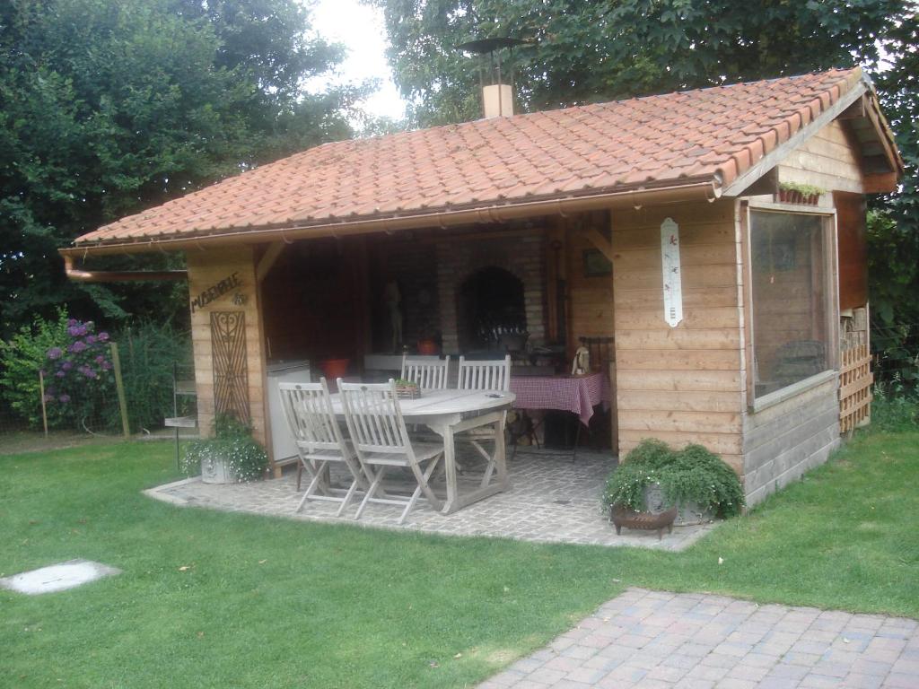 een paviljoen met een tafel en stoelen in een achtertuin bij B&B Mussenzele in Haaltert