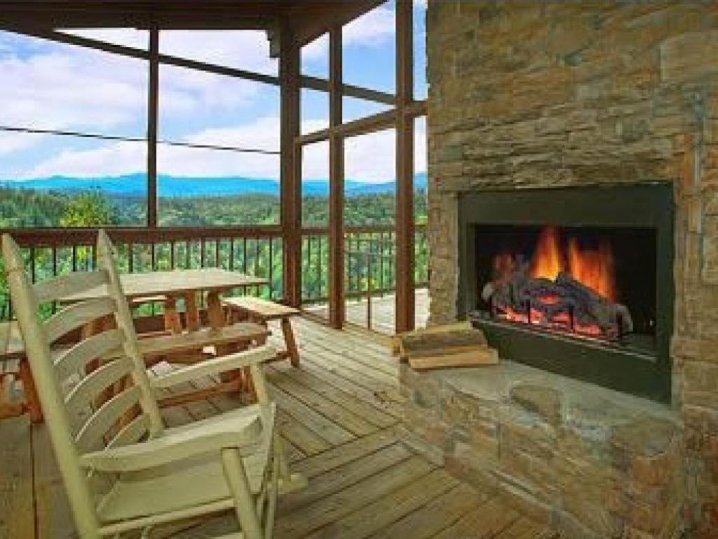 a fireplace on a deck with a table and chairs at Rocky Top Jewel Cabin in Park Settlement