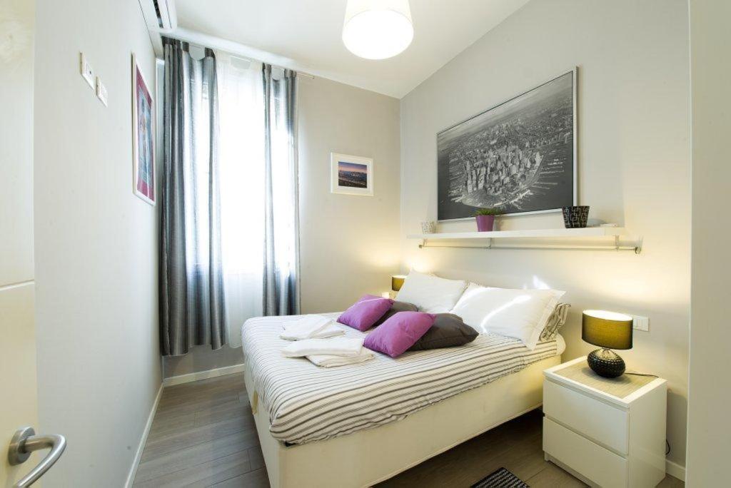 フィレンツェにあるアロッジオ カーサ トゥアのベッドルーム1室(白いシーツと紫色の枕が備わるベッド1台付)