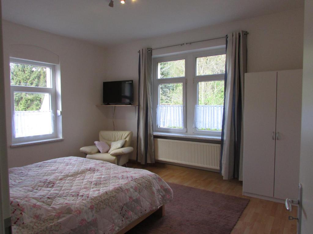 a bedroom with a bed and two windows and a chair at NoOaks in Meißen