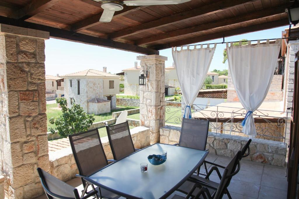 eine Terrasse mit einem Tisch und Stühlen auf dem Balkon in der Unterkunft Helen's Stone House in Siviri