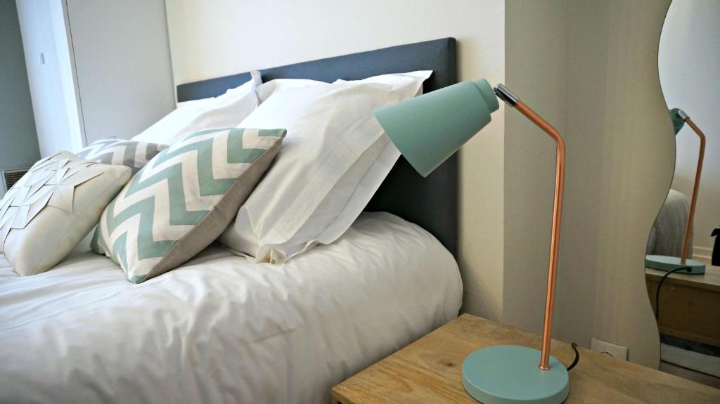 Una cama con almohadas blancas y una lámpara en una mesa. en Little Suite - Stella, en Lille
