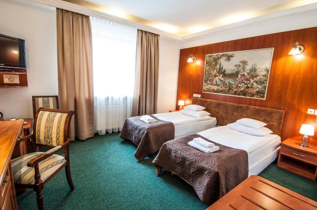 a hotel room with two beds and a chair at Hotel Artur in Kraków