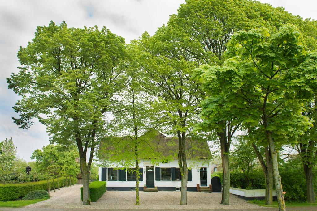 une maison blanche avec des arbres devant elle dans l'établissement De Heeren van Tuil, à Tuil