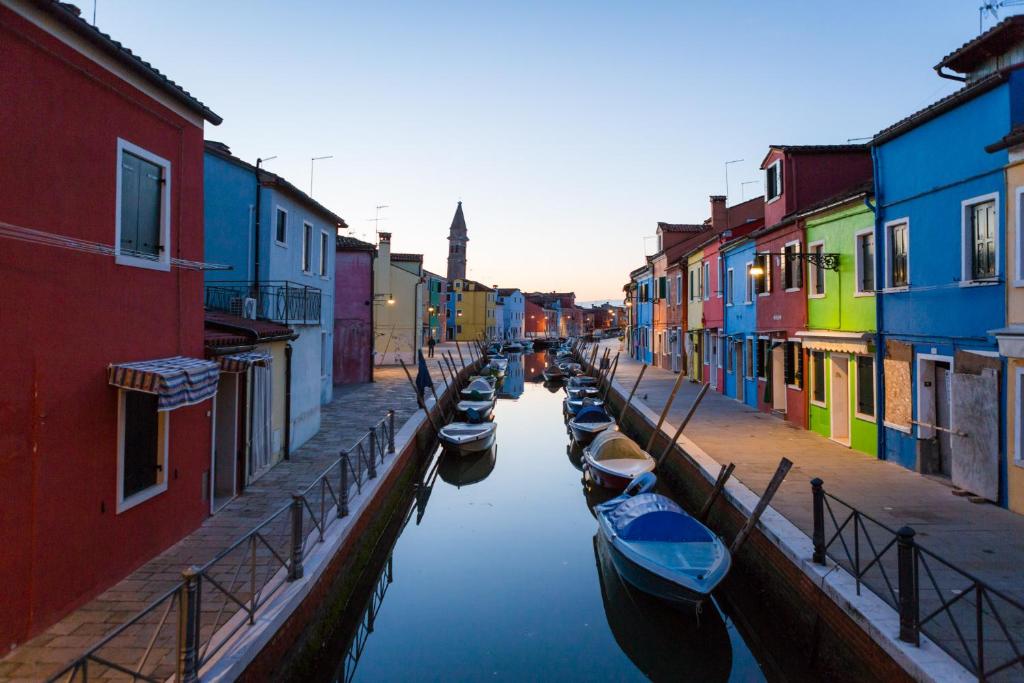 una fila de barcos en un canal con edificios coloridos en Casa Burano en Burano