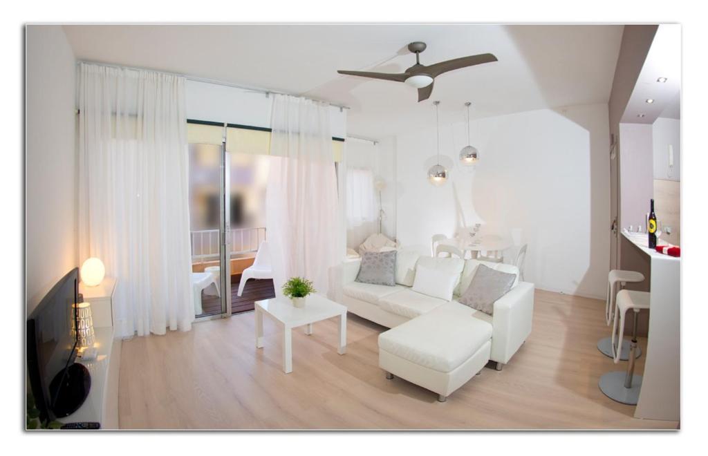 ein weißes Wohnzimmer mit einem weißen Sofa und einem Tisch in der Unterkunft White House Medano in El Médano