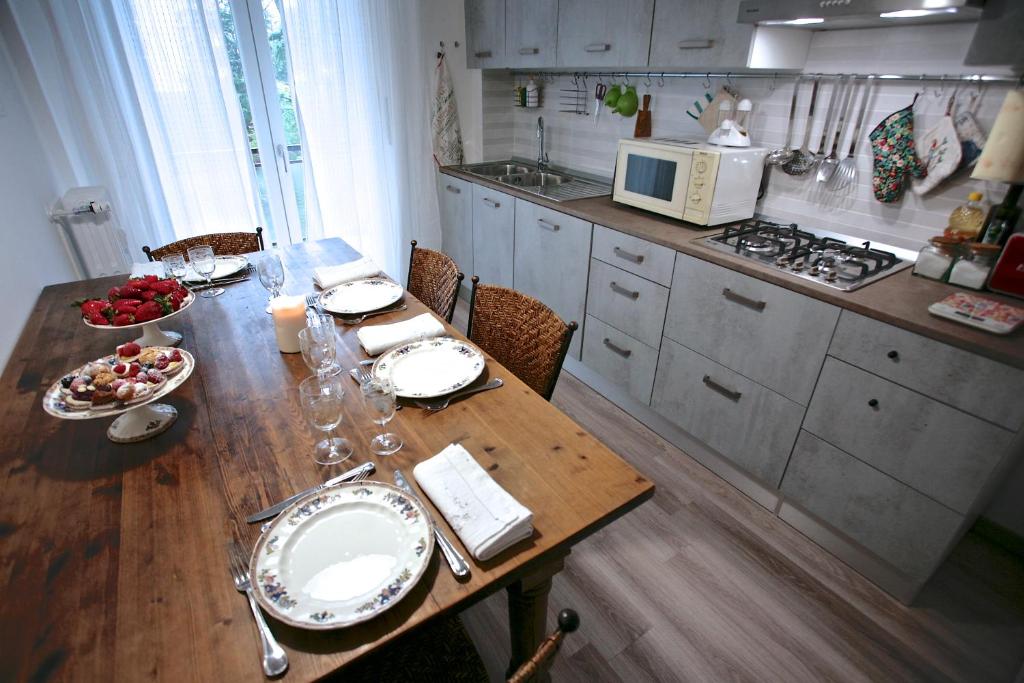Casa Scaletta Santa Lucia في بيرغامو: مطبخ مع طاولة خشبية مع لوحات واكواب للنبيذ