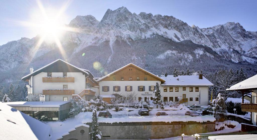 a building in the snow with a mountain in the background at Romantik Alpenhotel Waxenstein in Grainau