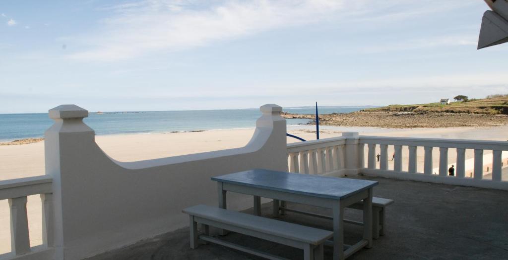 a table on a balcony with a view of the beach at Le Château de Sable in Plougasnou