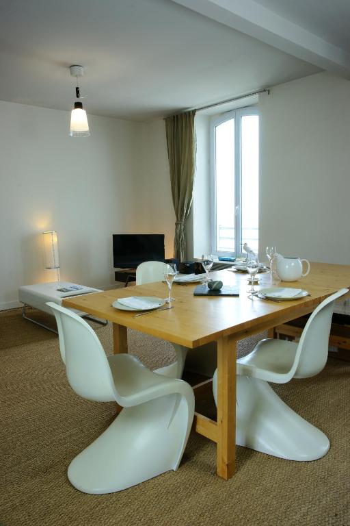 a wooden table with white chairs in a room at Le Château de Sable in Plougasnou