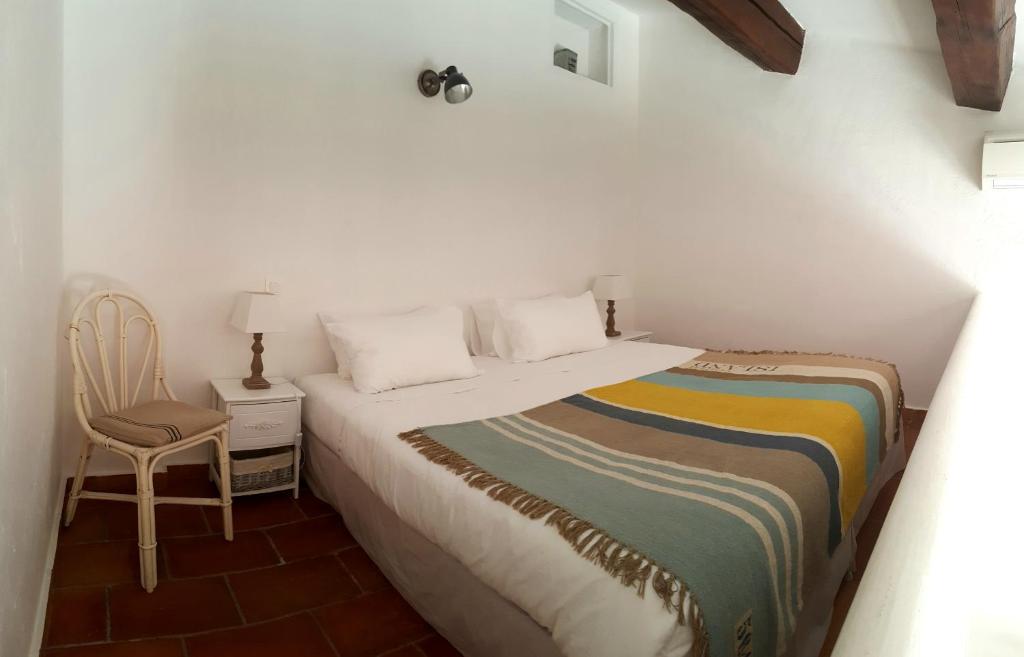 a white bedroom with a bed and a chair at Hôtel les Bouis - Vue mer in Saint-Tropez