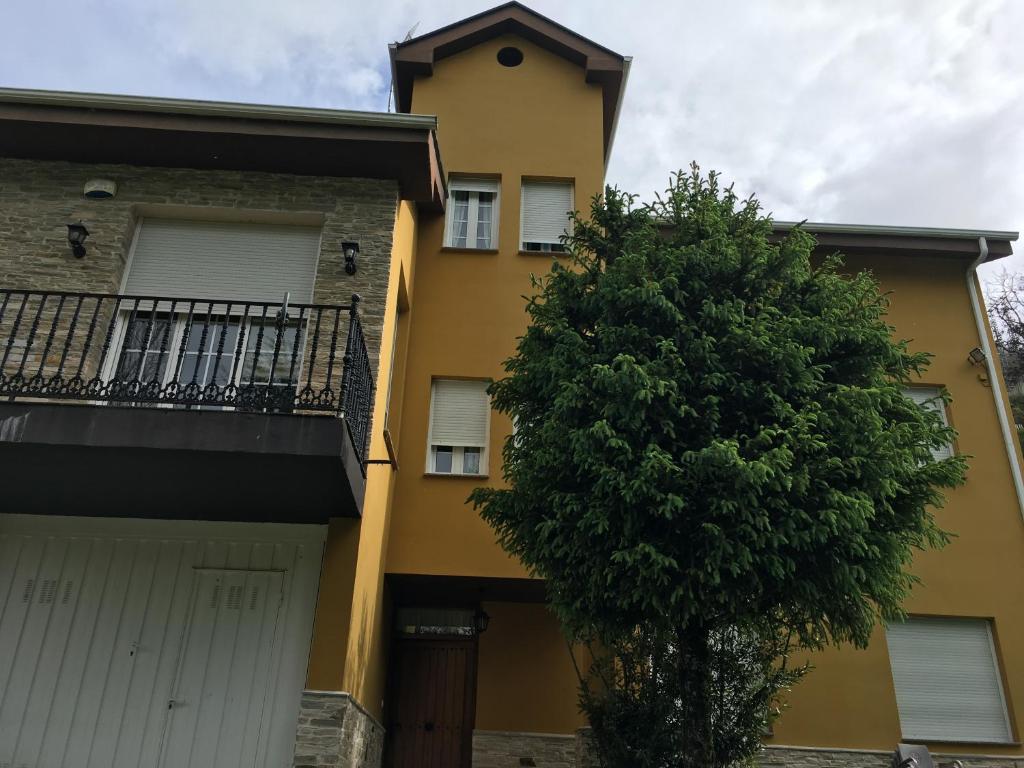 un edificio amarillo con un árbol delante de él en Os Arroxos en Trabadelo
