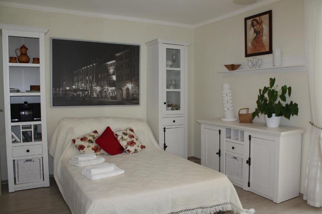 una camera bianca con letto con cuscini e asciugamani di Ferienwohnung Sonnenhaft a Baden-Baden