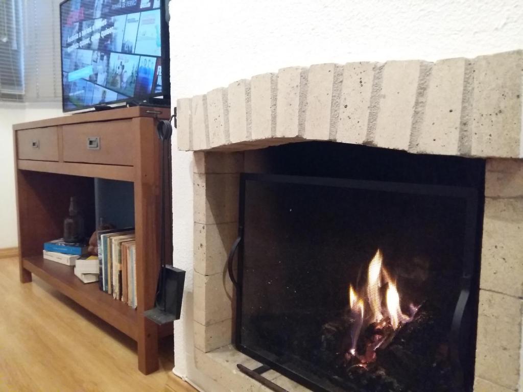chimenea con TV y chimenea en Apartamento Lago Grande Hotel, en Canela