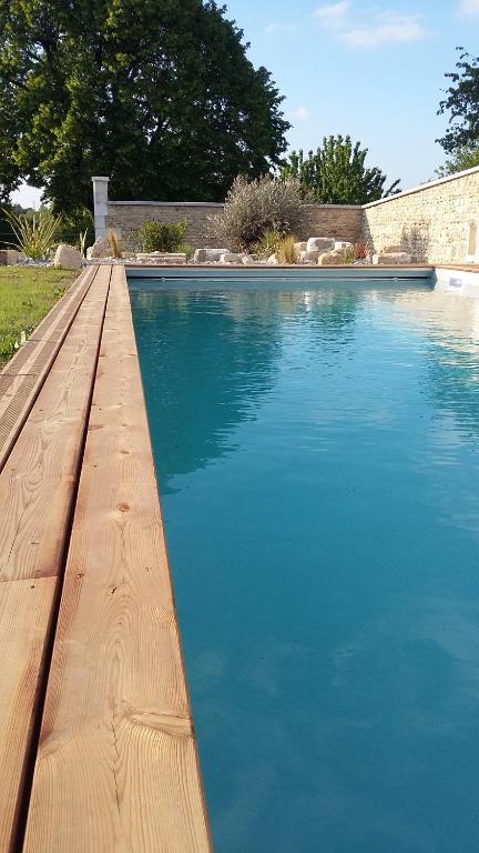 a pool of blue water with a wooden dock at Les Hauts De Chalonne in Le Gond-Pontouvre