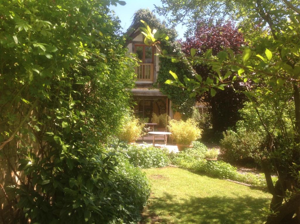 une maison avec un banc au milieu d'un jardin dans l'établissement Au Fond du Jardin Maison d'hôtes, à Saint-Saëns