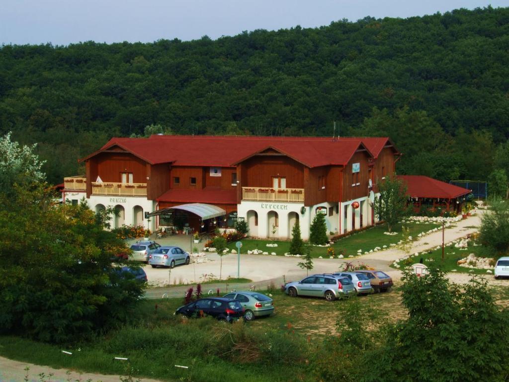 a large building with cars parked in a parking lot at Pollushof Panzió és Étterem in Csolnok