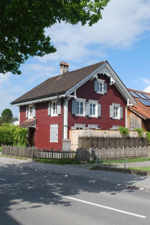 a red house with a fence on the side of the road at Ferienwohnung Rheintal in Feldkirch