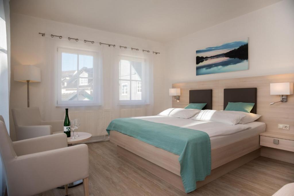 una camera con un grande letto e una sedia di Hotel Zum Bären a Rüdesheim am Rhein