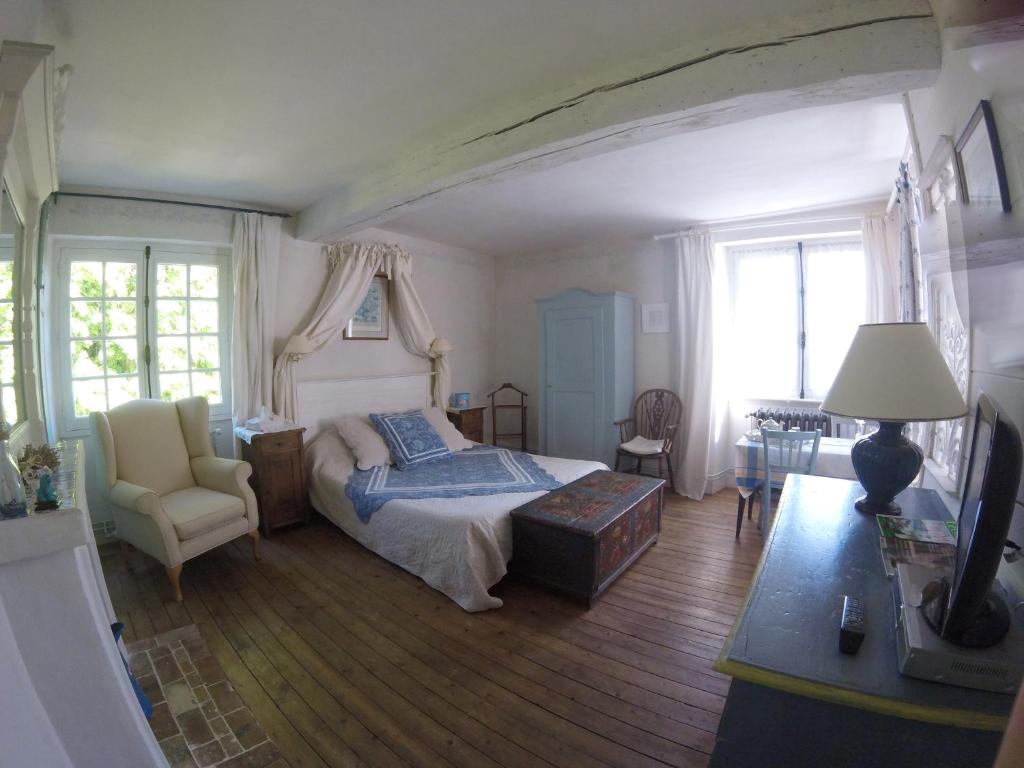 ein Schlafzimmer mit einem Bett und einem Stuhl in der Unterkunft Clos de la Rose in Saint-Cyr-sur-Morin