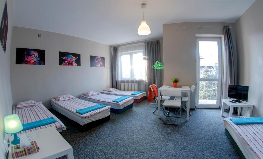 Pokój z 4 łóżkami, biurkiem i telewizorem w obiekcie Place4Us w Warszawie
