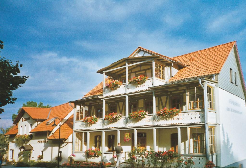 ein großes weißes Gebäude mit Blumen auf den Balkonen in der Unterkunft Hotel Pension Am Kurzentrum in Bad Suderode