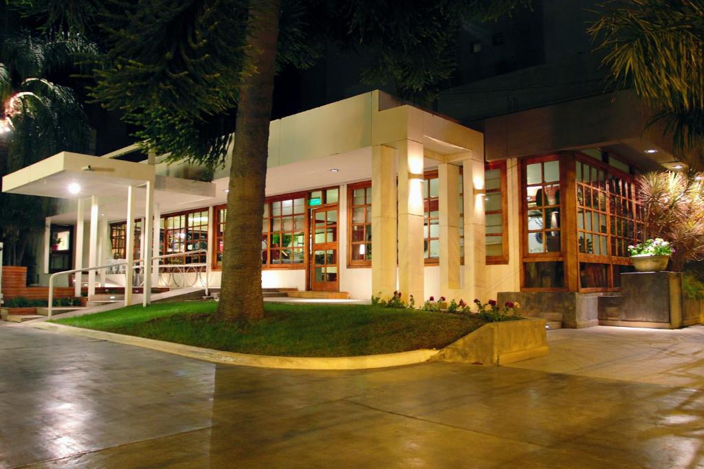 un edificio con un árbol delante de él por la noche en Hotel Libertador en Santiago del Estero