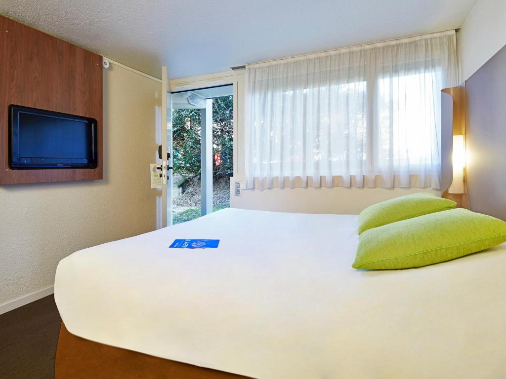 a large white bed in a room with a window at Campanile Marne la Vallée - Chelles in Chelles