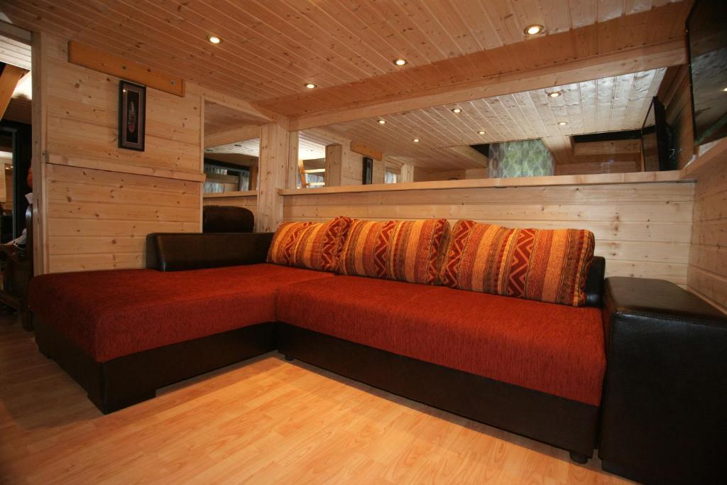 セゲドにあるTattoo Apartmanの木製の壁の客室内に大きな赤いソファ