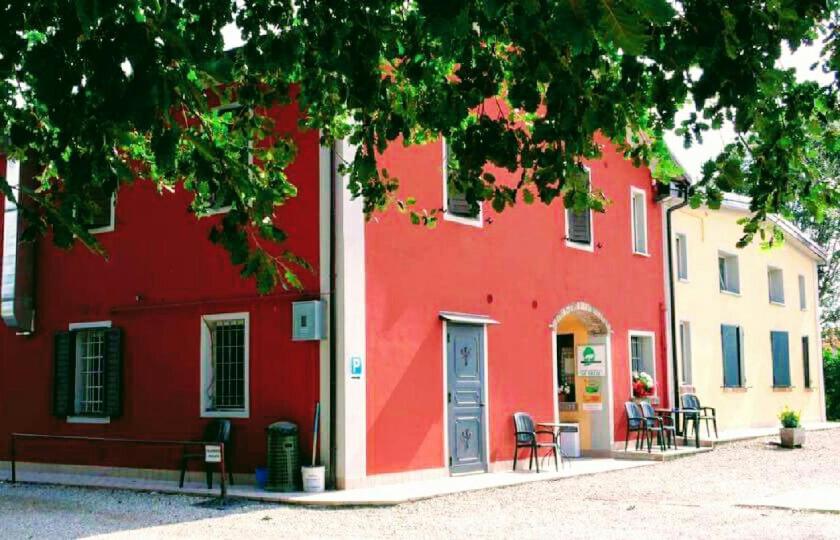 un edificio rojo con sillas y una mesa frente a él en Agriturismo Le Gazze, en Camposanto