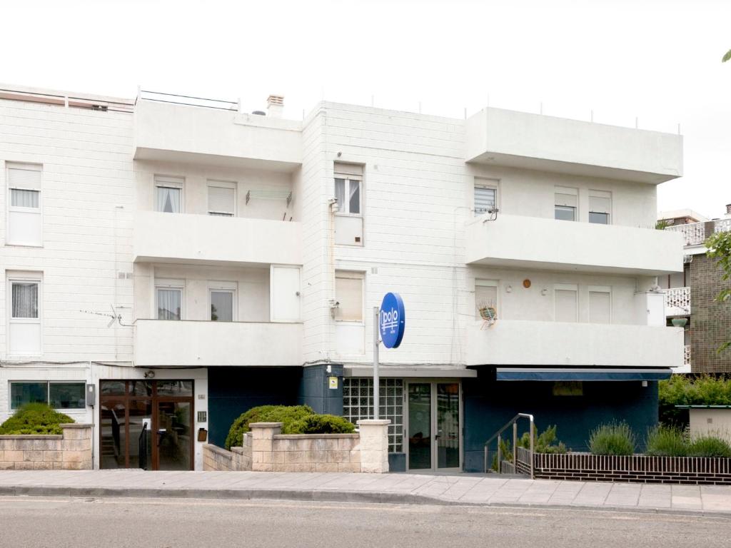 un bâtiment blanc au coin d'une rue dans l'établissement Apartamentos Apolo Somo, à Somo