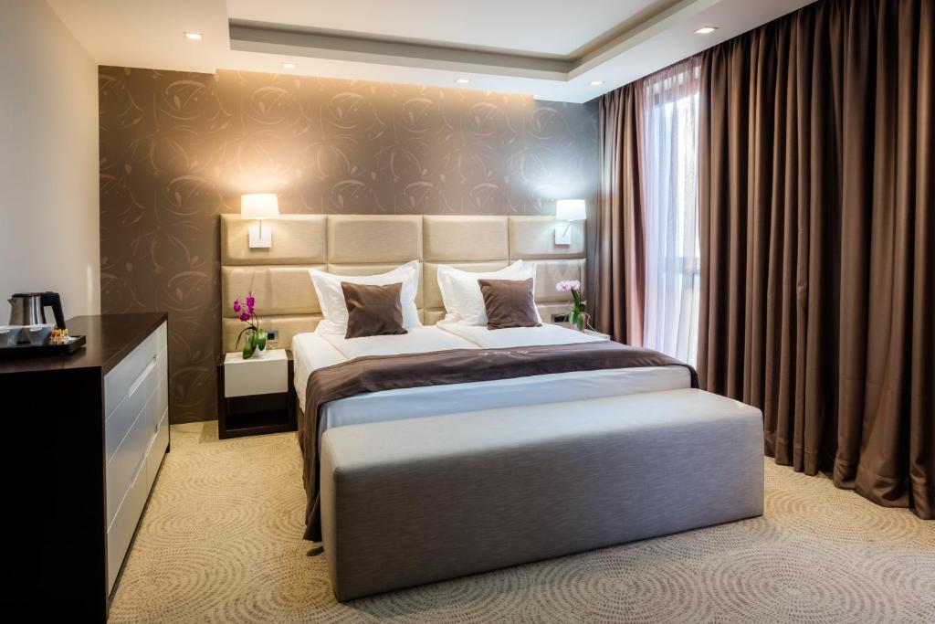 um quarto com uma cama grande e uma janela em VIKO Boutique Apart Hotel em Sófia