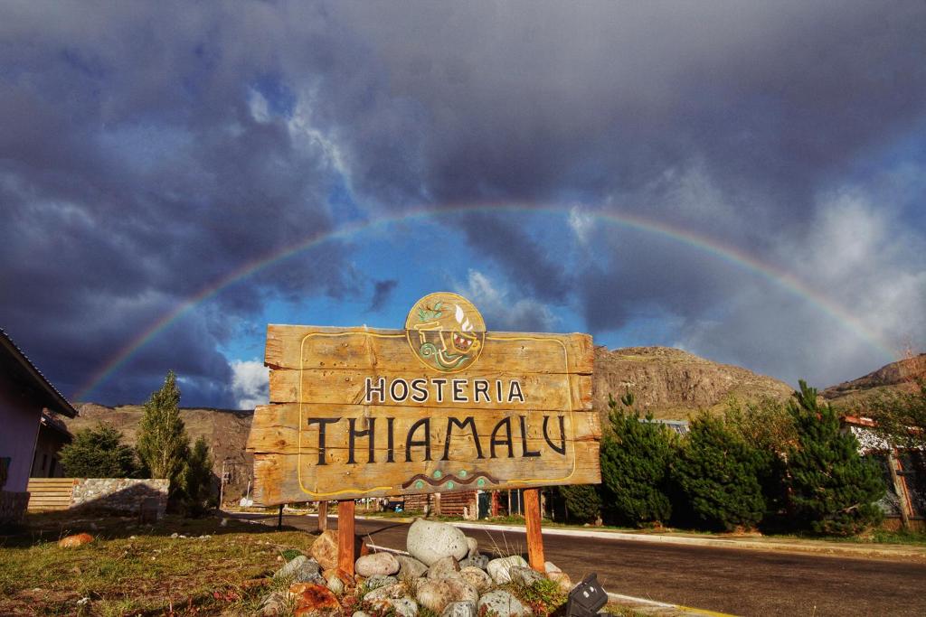 un arco iris en el cielo sobre una señal con una señal en Hosteria Thiamalu en El Chaltén