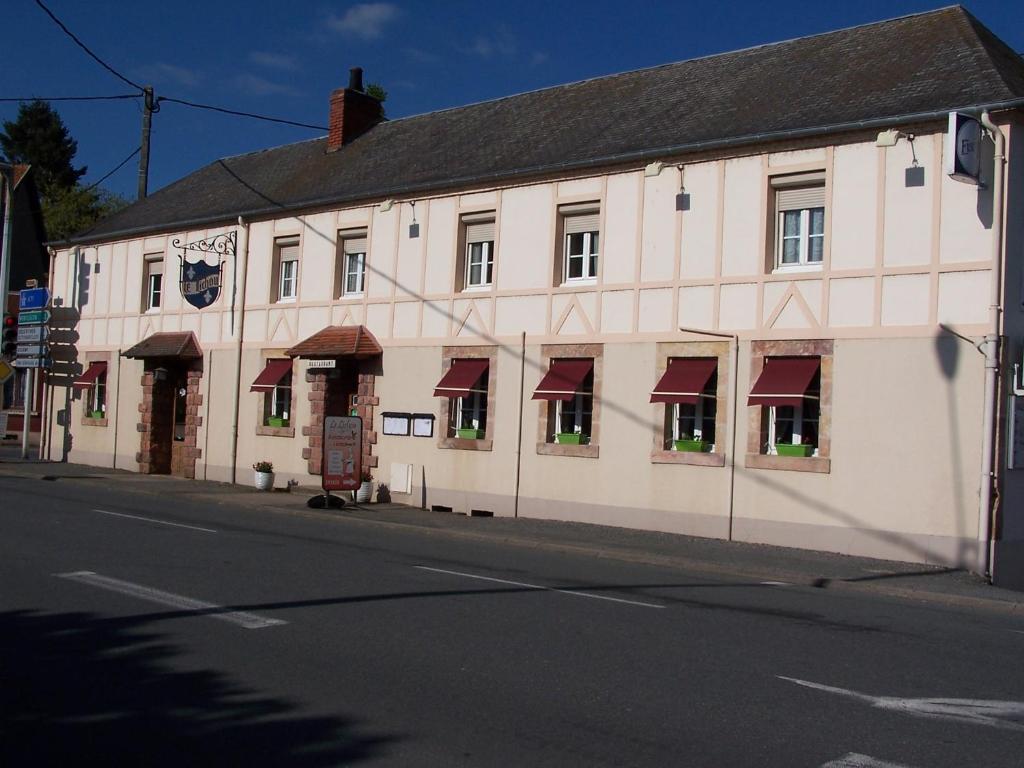 a large white building with red awnings on a street at le lichou in Vallon-en-Sully