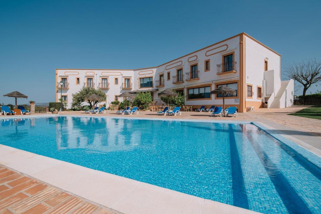 a swimming pool in front of a building at Quinta dos Poetas Nature Hotel & Apartments in Olhão