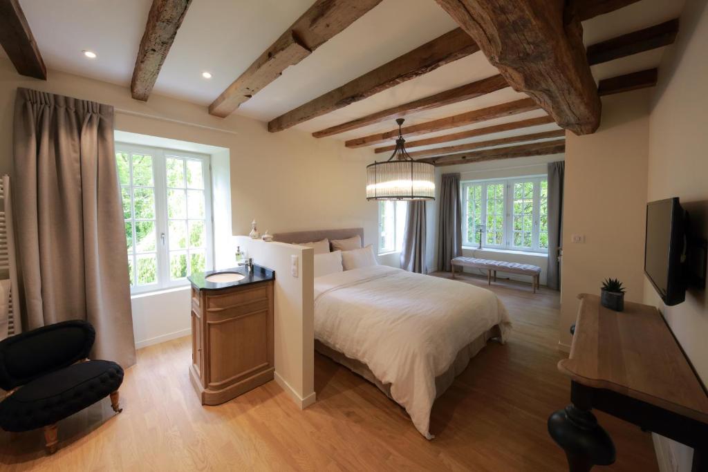 a bedroom with a bed and a desk and two windows at Le Moulin De Nanteuil in Migné-Auxances