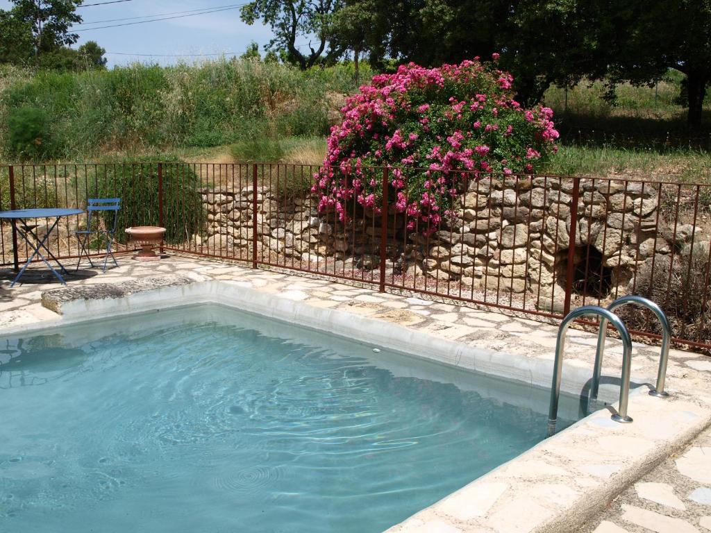 una piscina con una valla y flores rosas en jardin d'antan en Ansouis