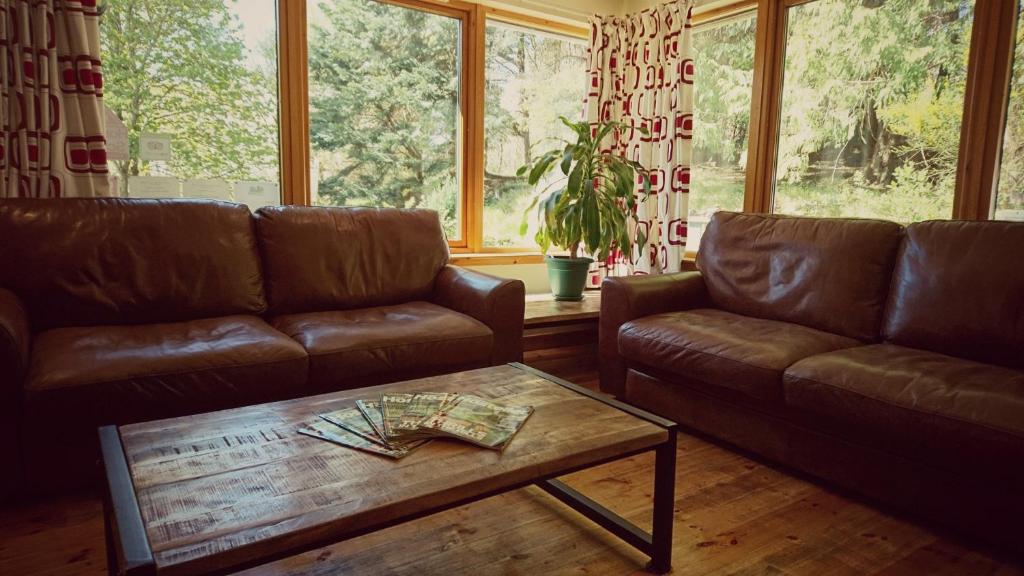 a living room with two leather couches and a coffee table at Morag's Lodge in Fort Augustus