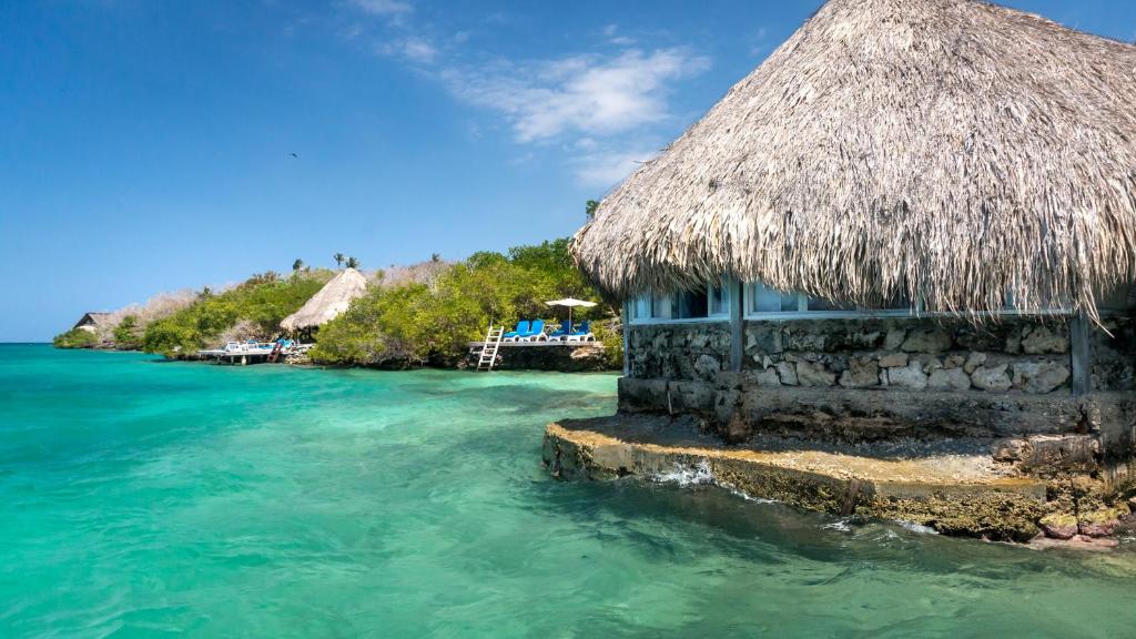 um edifício com um telhado de palha na água em Hotel Coralina Island em Isla Grande