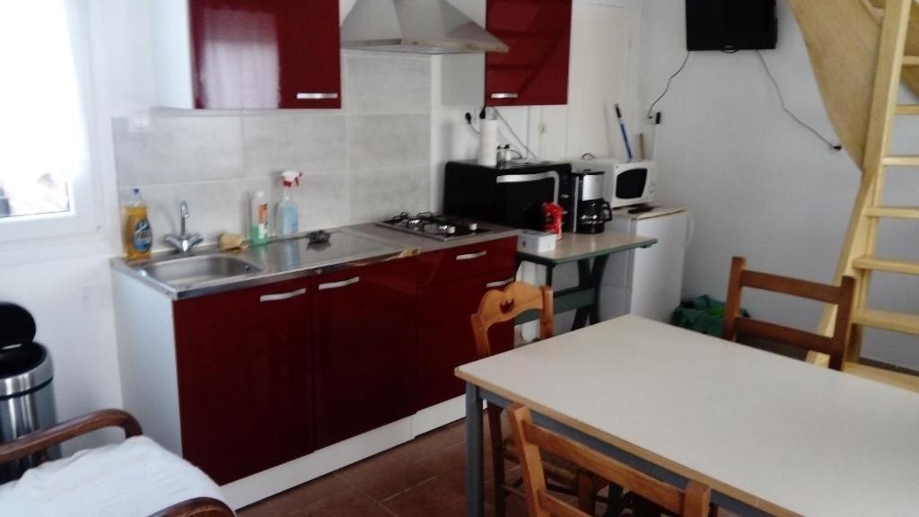 a kitchen with red cabinets and a sink and a table at Gîte de Blessy in Blessy