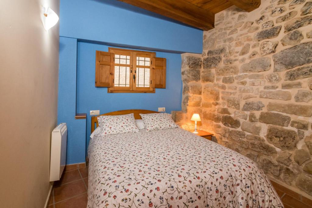 a bedroom with a bed in a stone wall at Apartamentos Plaza Mayor in Valderrobres